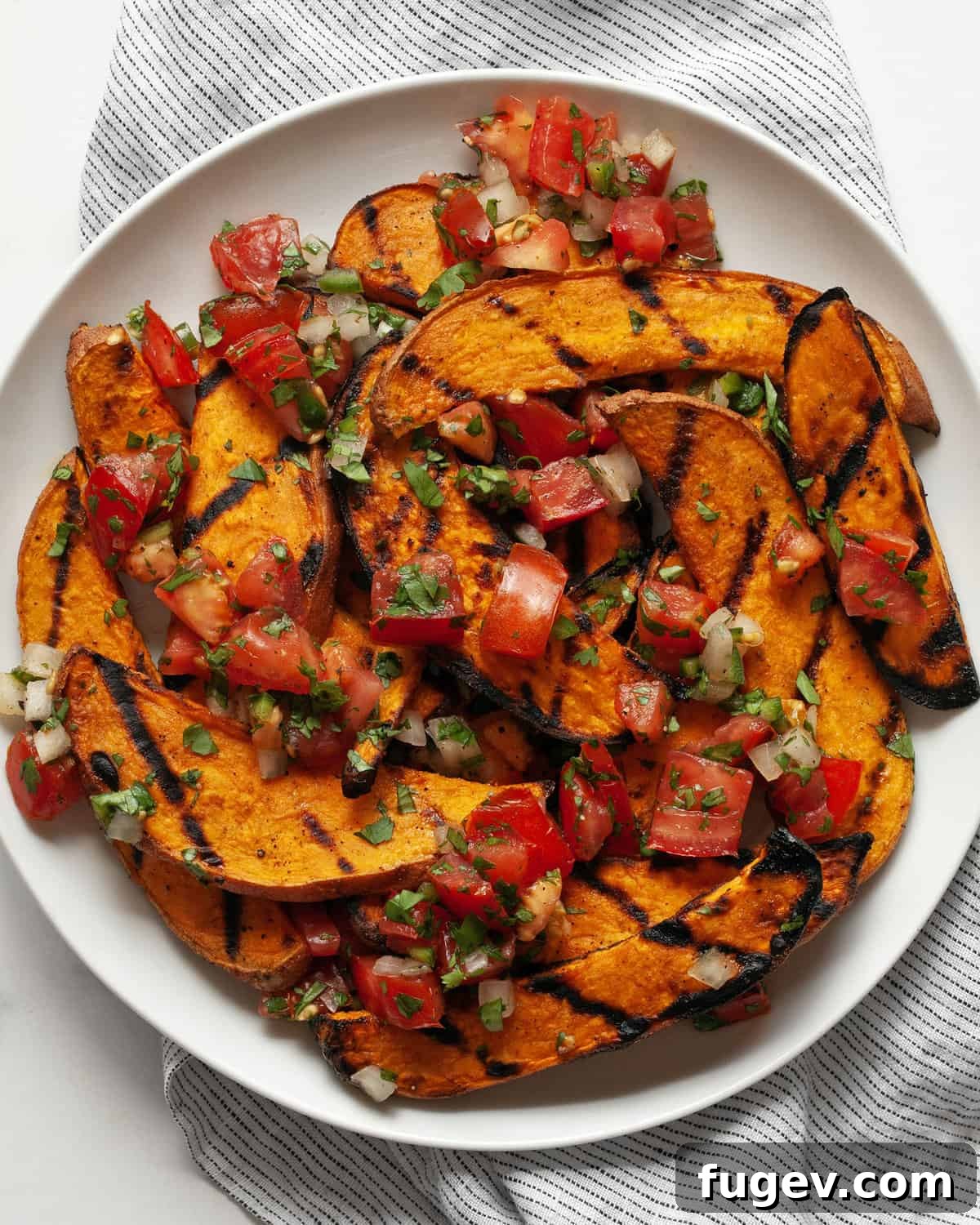 Effortlessly Delicious Grilled Sweet Potatoes 2 Grilled sweet potatoes generously topped with vibrant homemade pico de gallo, served on a rustic plate.