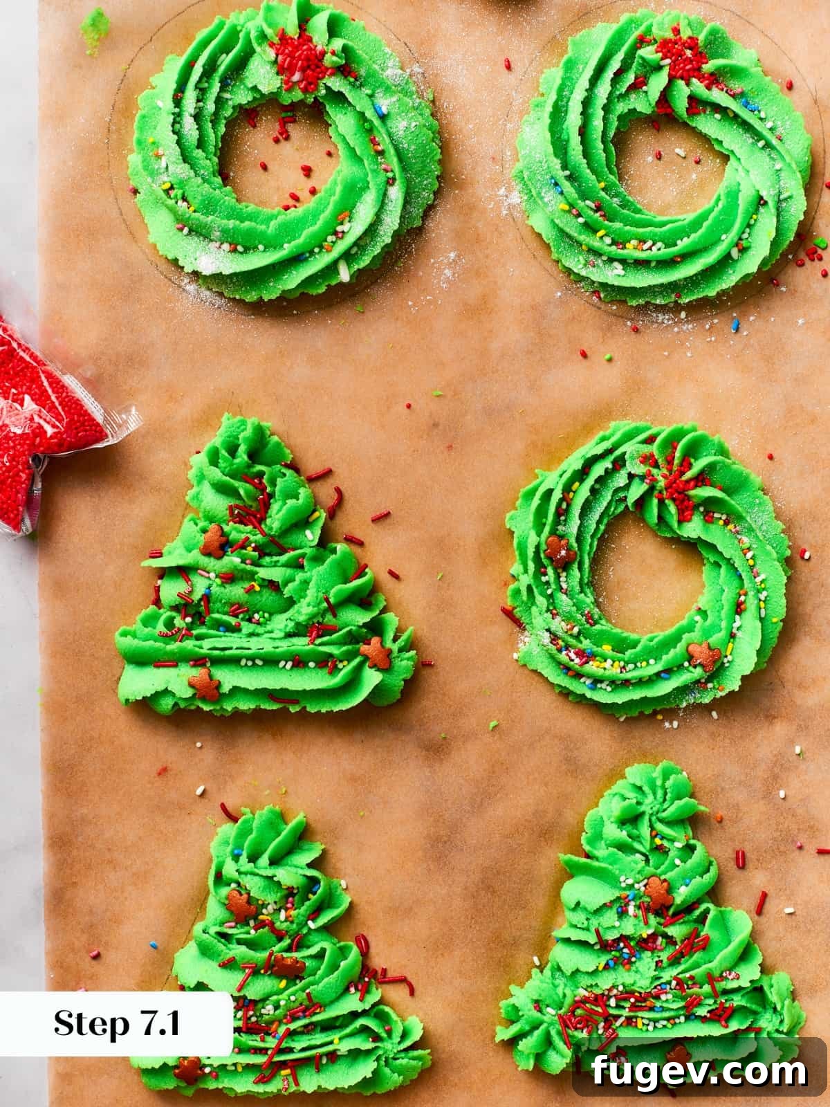 Easy Spritz Cookie Perfection 10 Piped wreath and tree shapes of spritz cookie dough lined neatly on parchment paper before baking.