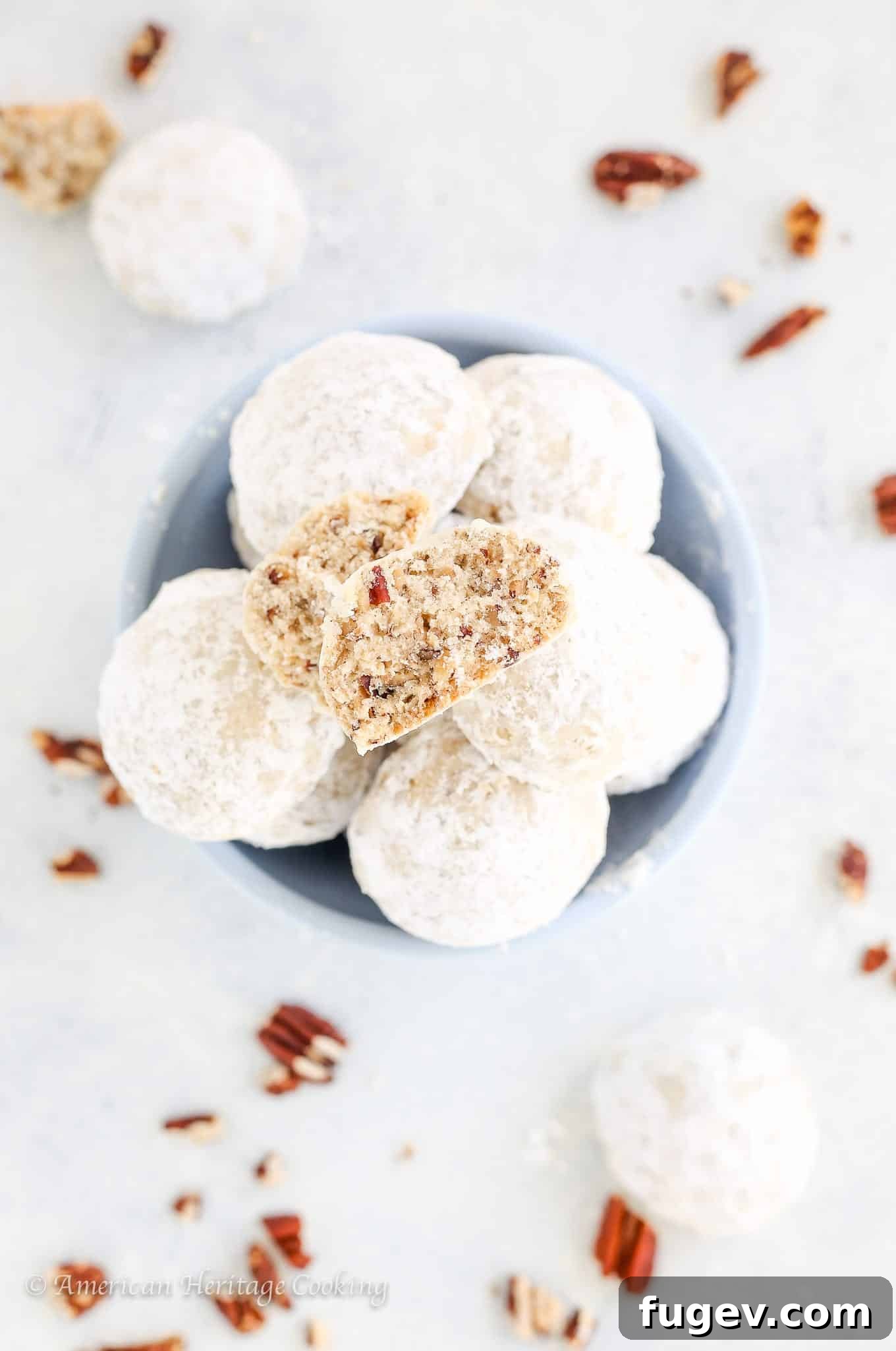 Fiesta Snowball Cookies 3 Close-up of Mexican wedding cookies on a white countertop with whole pecans scattered around.