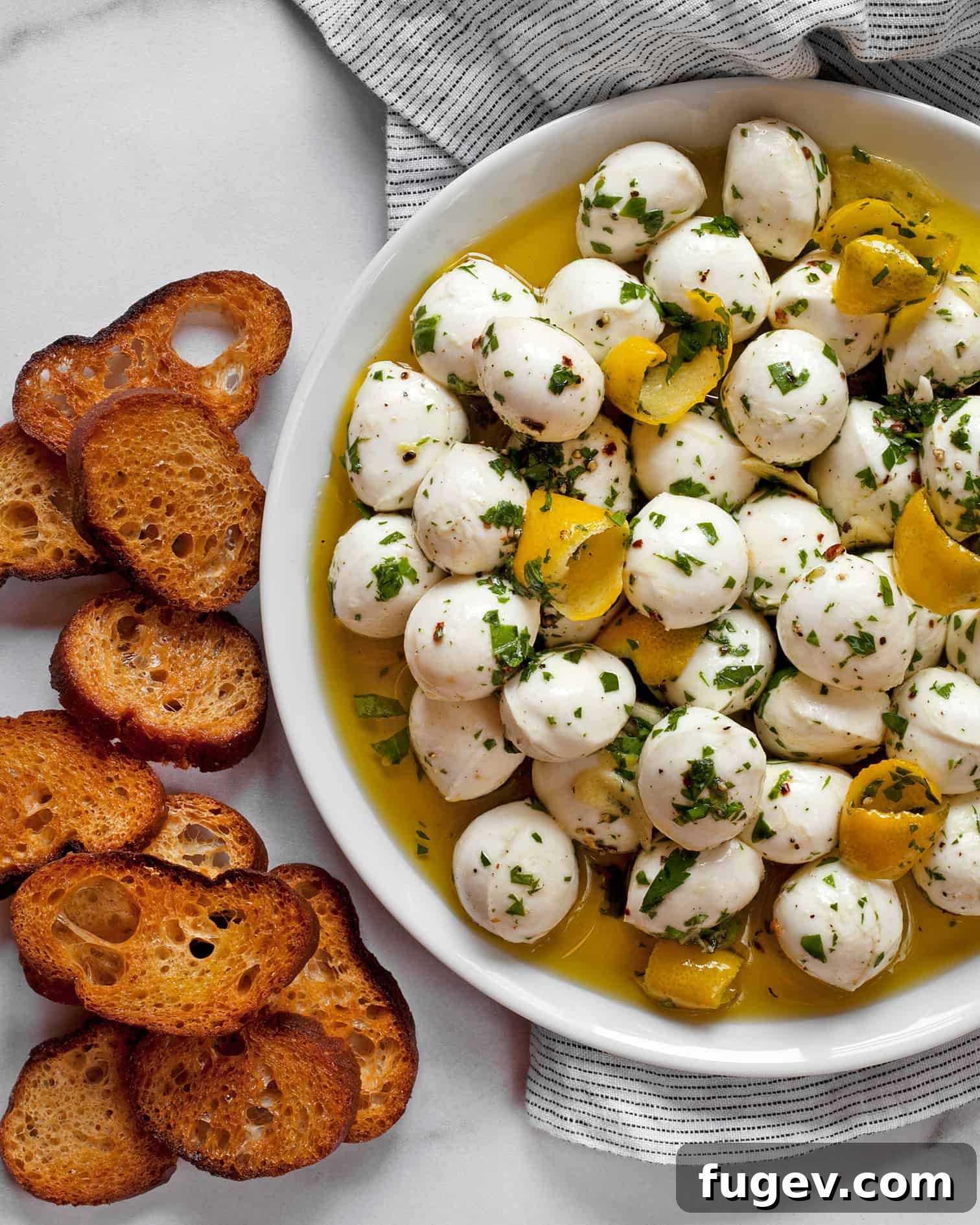 Zesty Mozzarella Pearls 2 Marinated Mozzarella Balls with Toasted Bread, infused with herbs and lemon.