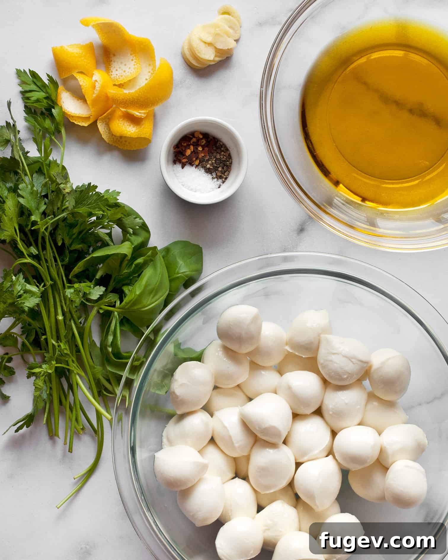 Zesty Mozzarella Pearls 3 Ingredients laid out for marinated mozzarella, including fresh herbs, lemon, garlic, and olive oil.