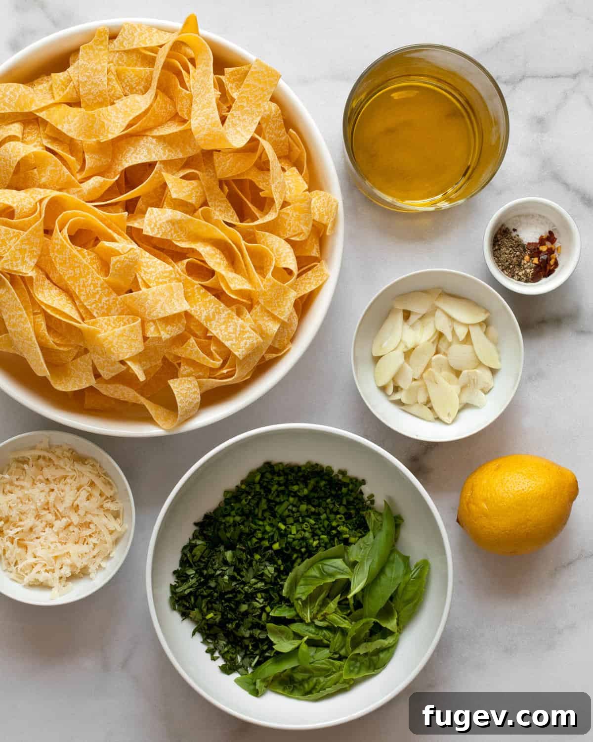 Vibrant Fresh Herb Pappardelle 3 Lay-flat image of fresh ingredients for pappardelle pasta including pasta nests, olive oil, lemons, various fresh herbs, garlic cloves, and a block of Parmesan cheese.