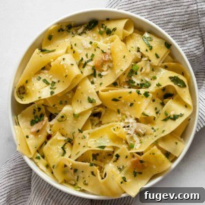 Herb pappardelle pasta in a small bowl, garnished with fresh herbs.