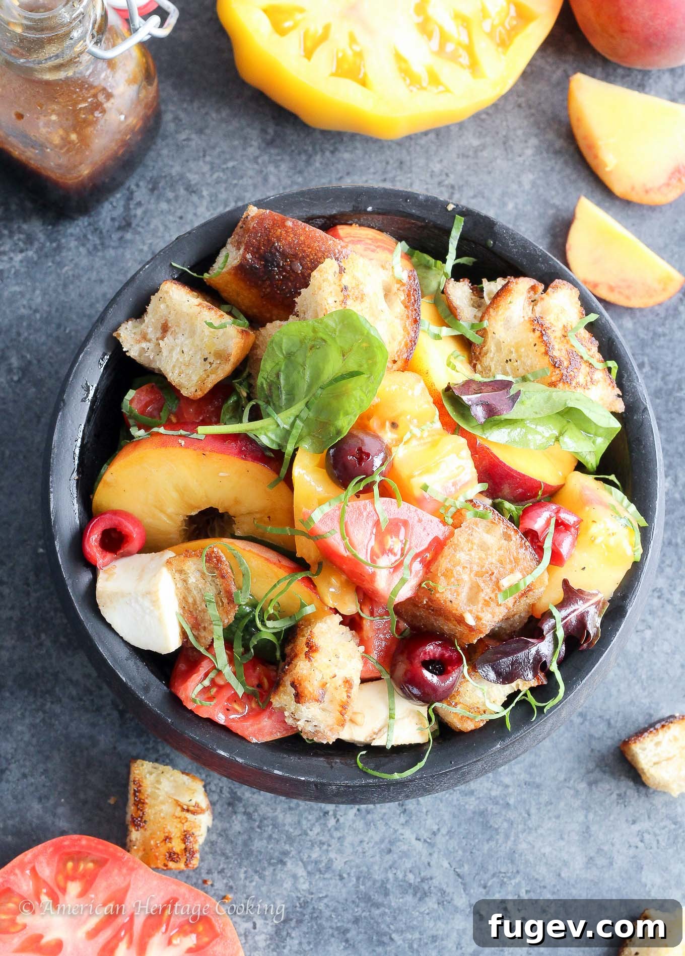 Orchard Fresh Caprese Panzanella 4 Overhead shot of Stone Fruit Caprese Panzanella Salad with a serving spoon, garnished with more fresh basil leaves.