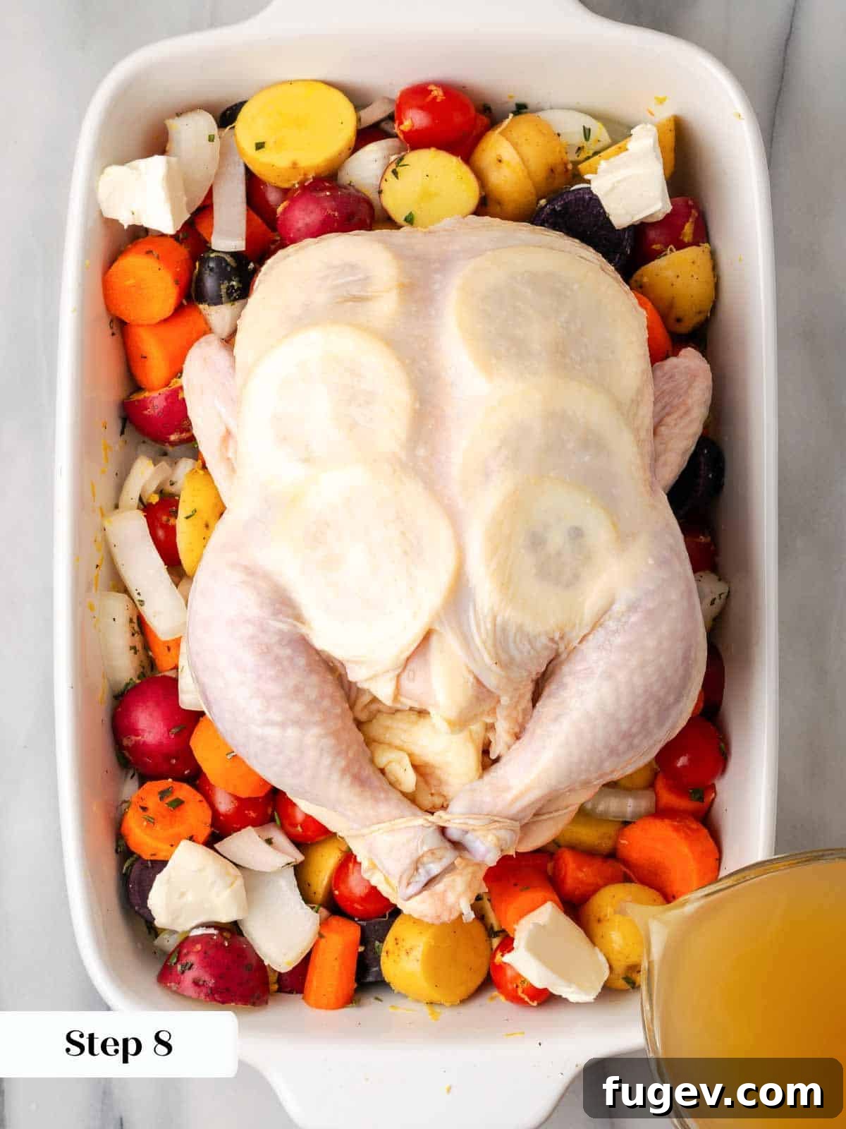 Zesty Lemon Roasted Chicken 7 trussed chicken on vegetables in white roasting dish.