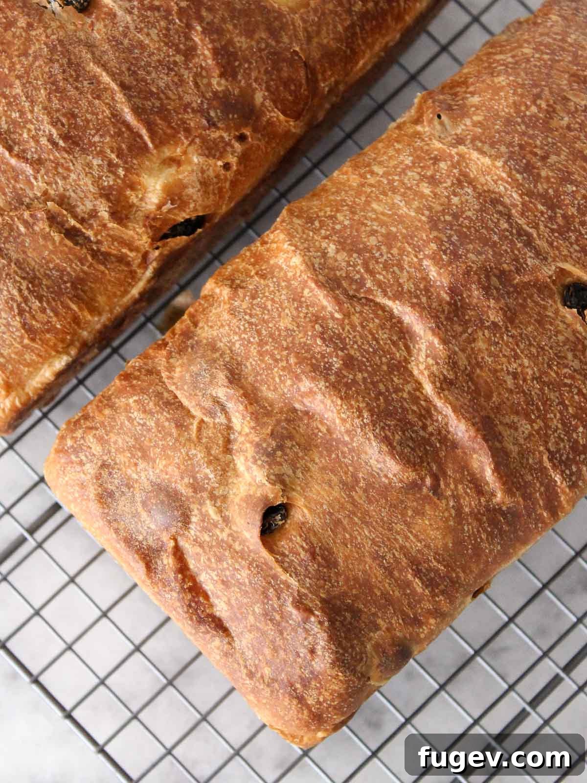 Artisan Sourdough Raisin Loaf 8 Two freshly baked sourdough raisin loaves cooling on a wire rack.