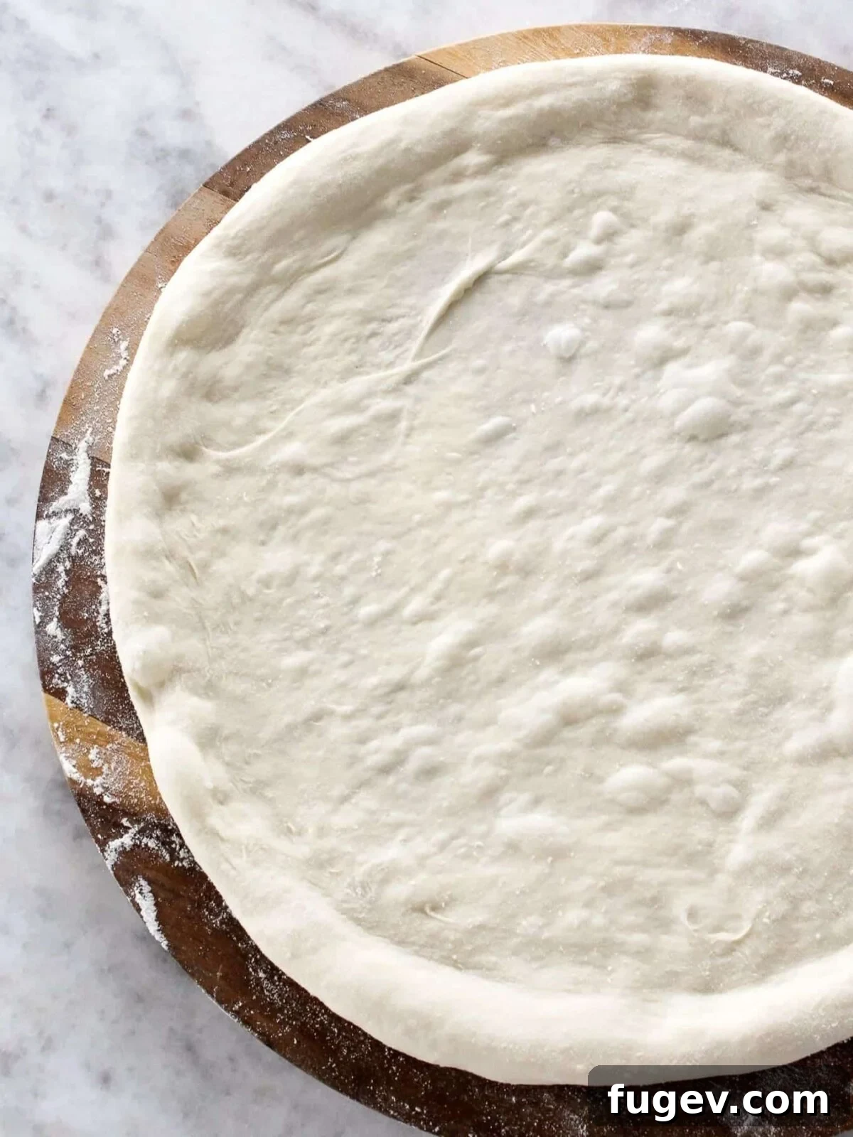 Artisan Sourdough Pizza Dough 2 Unbaked sourdough pizza dough with raised edges and flour dusting, ready for toppings.