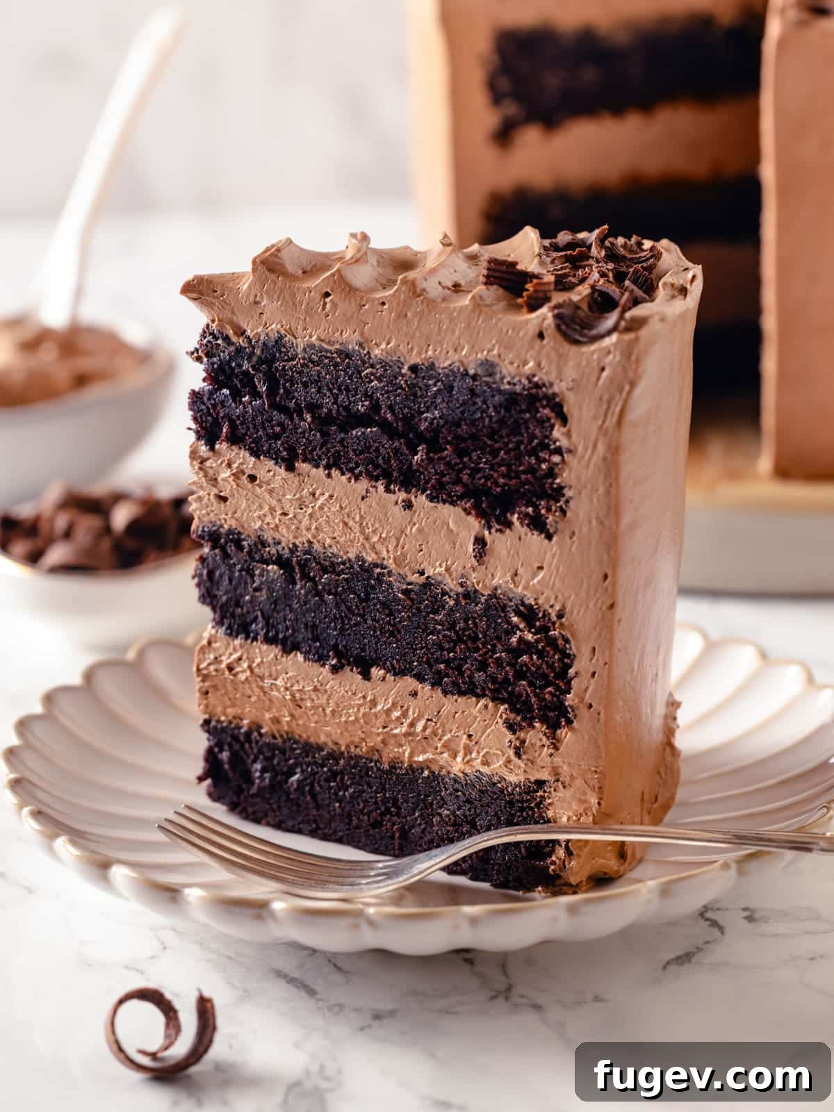 Sinfully Rich Chocolate Delight 2 Triangular slice of Devil’s food cake garnished with chocolate curls beside it, showcasing its moist layers and smooth frosting.