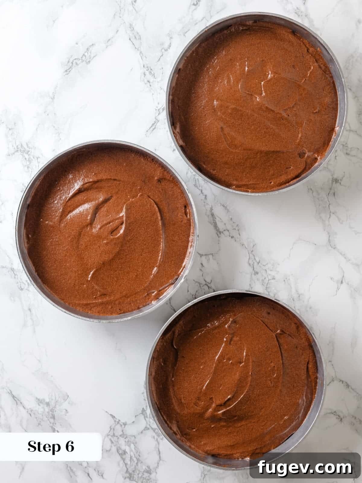 Sinfully Rich Chocolate Delight 13 Rich chocolate cake batter evenly portioned into three round baking pans, ready to be placed in the preheated oven.