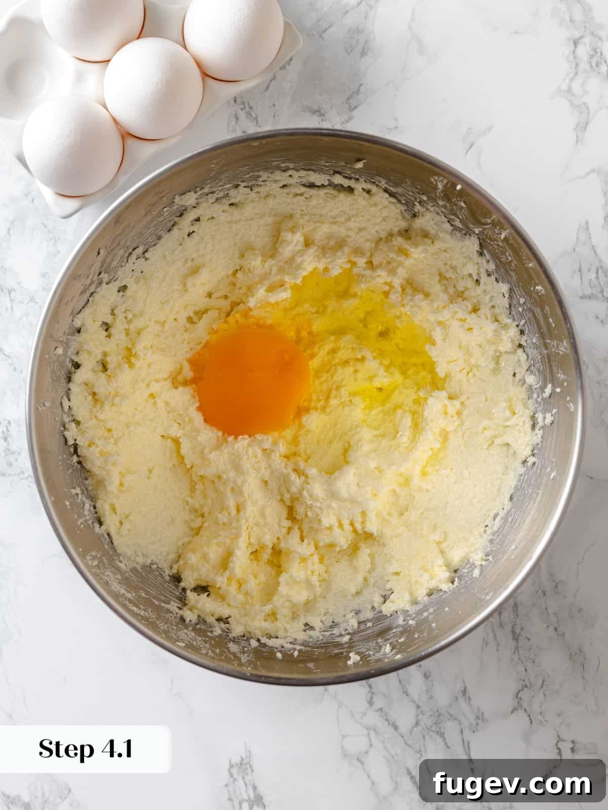 Sinfully Rich Chocolate Delight 8 Eggs being gradually mixed into the creamed butter and sugar mixture, ensuring proper emulsification for the cake batter.