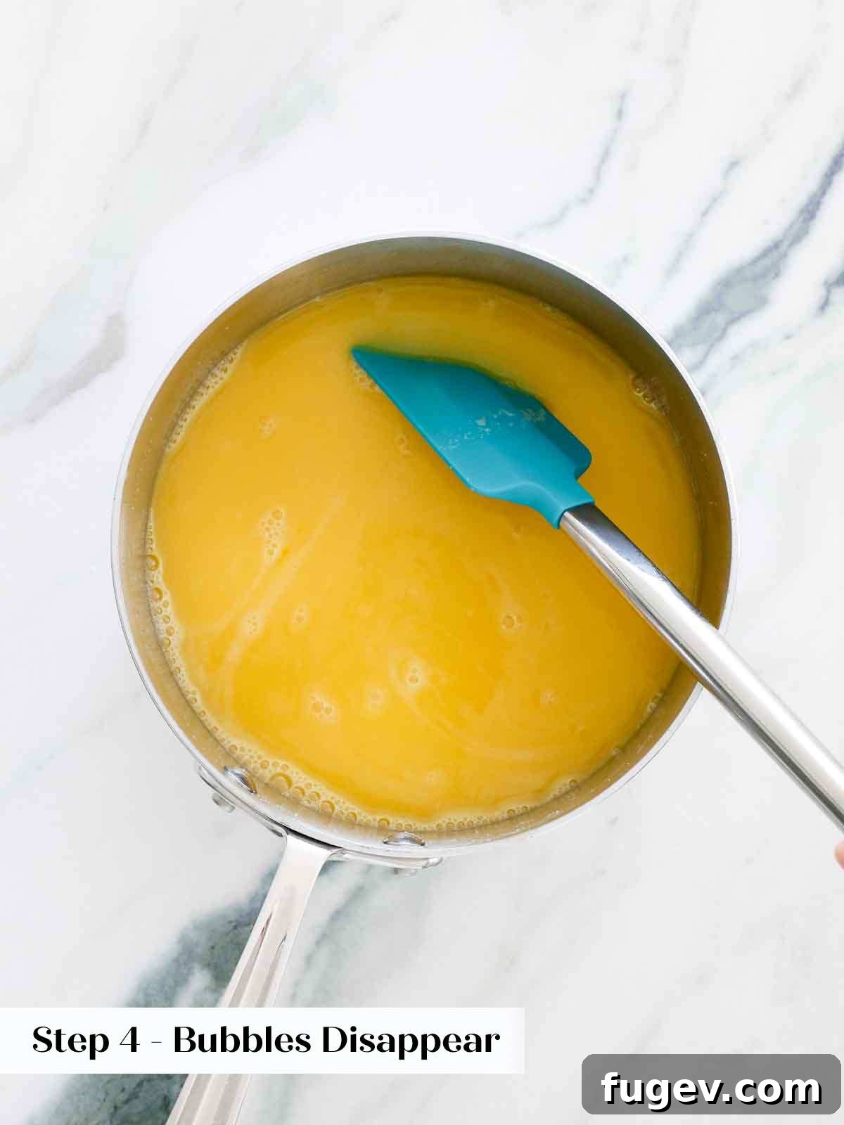 Bright & Tangy Lemon Curd 8 The lemon curd mixture being cooked on the stovetop in a saucepan, with a whisk actively stirring the contents to ensure even heating and prevent lumps.