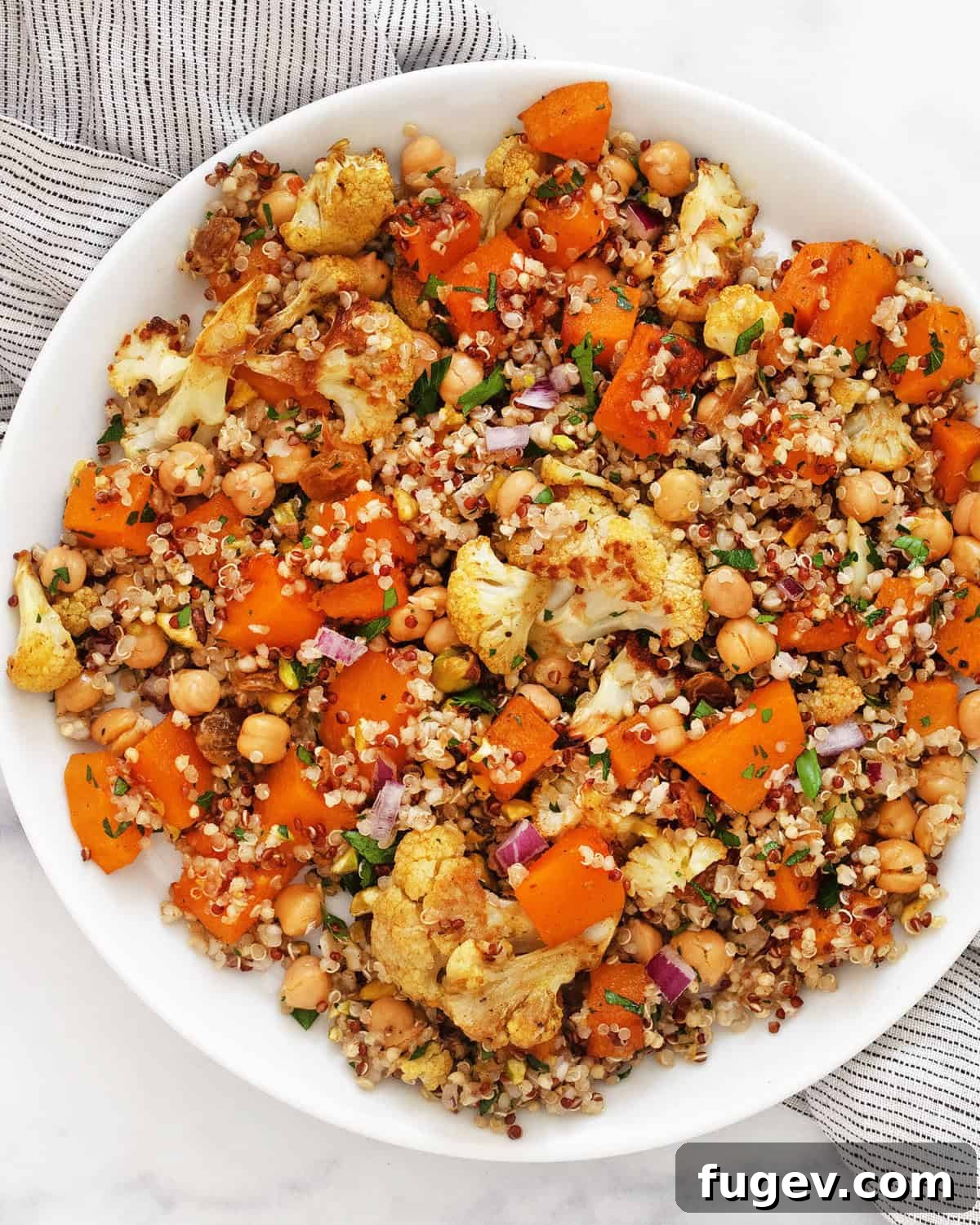Hearty Roasted Butternut Squash and Cauliflower Quinoa 2 A beautifully arranged plate of roasted butternut squash and cauliflower quinoa, garnished with fresh herbs and pistachios.