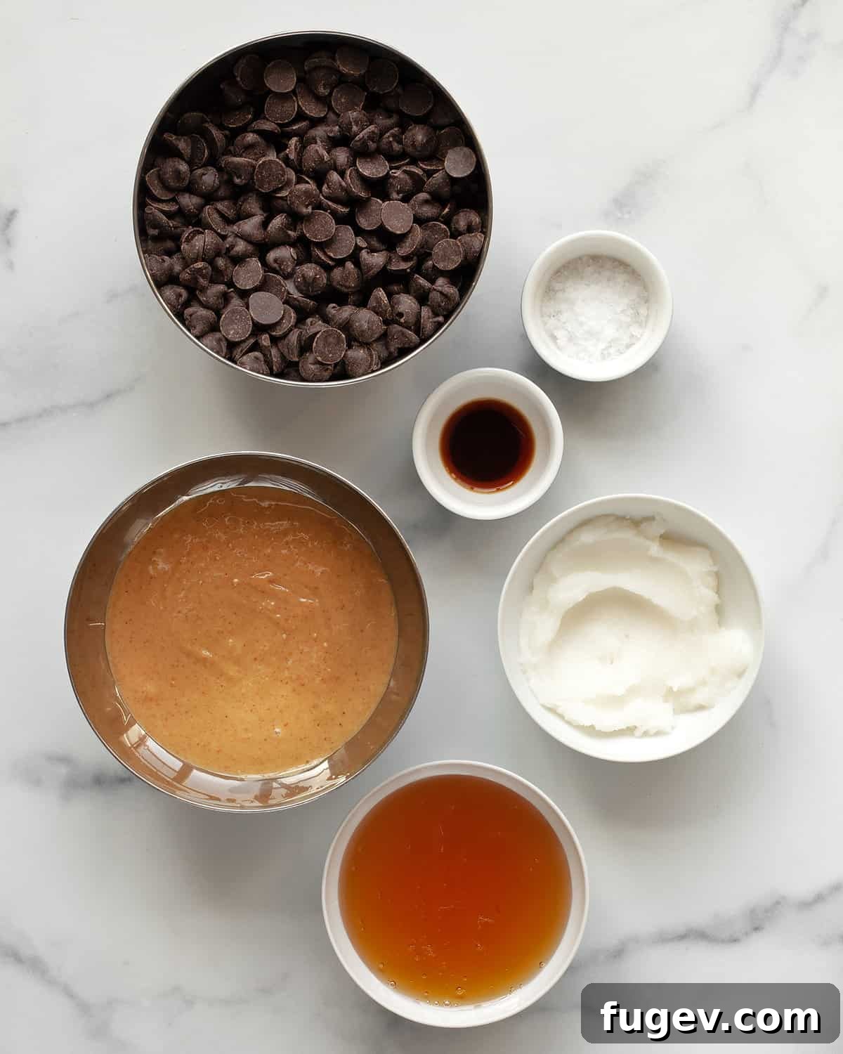 DIY Peanut Butter Delights 3 Ingredients including dark chocolate chips, peanut butter, honey, coconut oil, vanilla extract and flaky sea salt laid out on a surface.