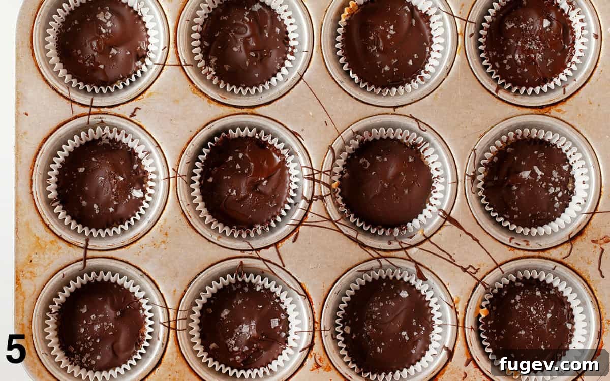 DIY Peanut Butter Delights 6 Homemade peanut butter cups in a muffin pan after the final chocolate layer and sea salt.