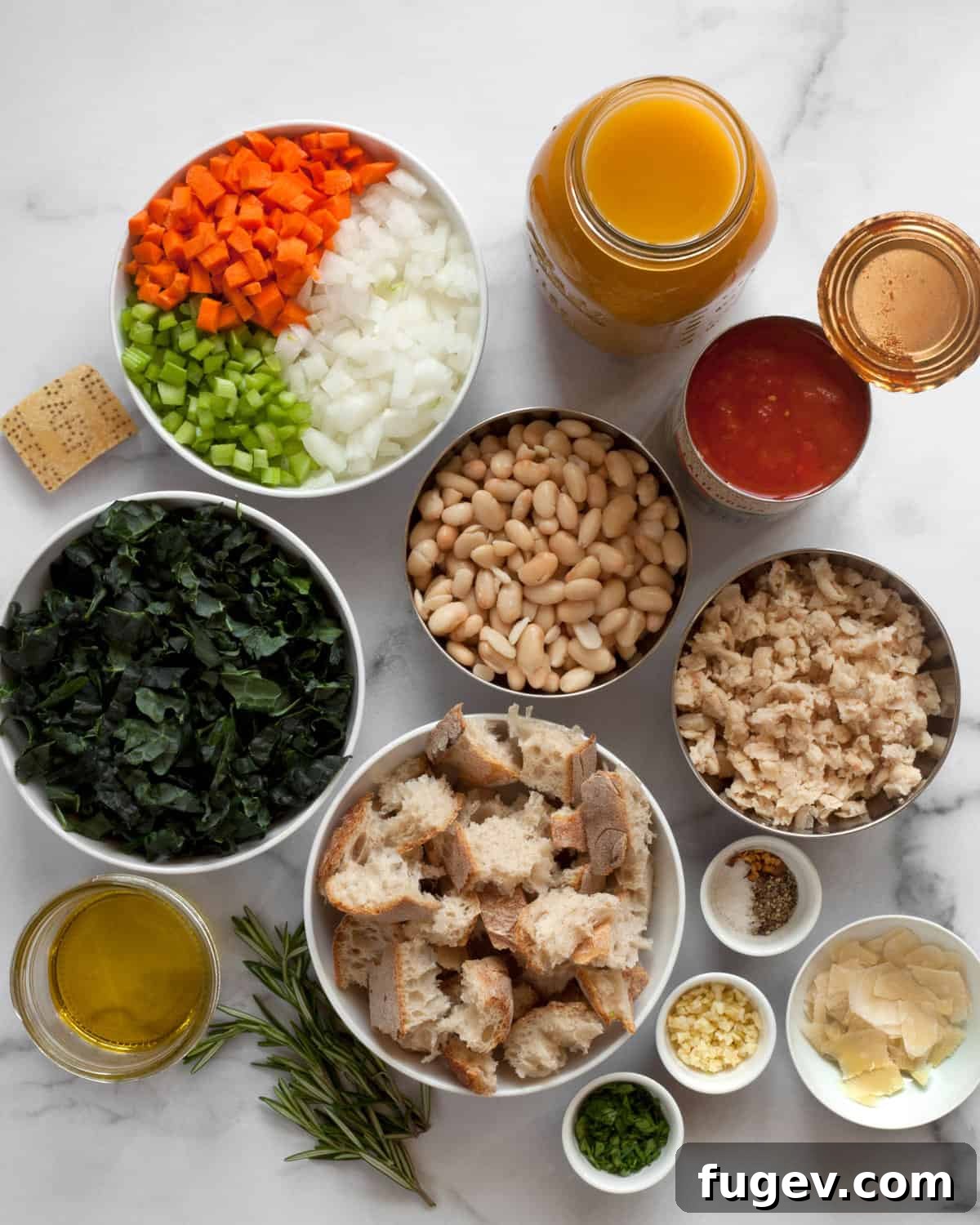 Rustic Tuscan White Bean Soup 3 Ingredients including white beans, canned tomatoes, broth, carrots, celery, onions, garlic, olive oil, rosemary and spices laid out on a wooden surface.