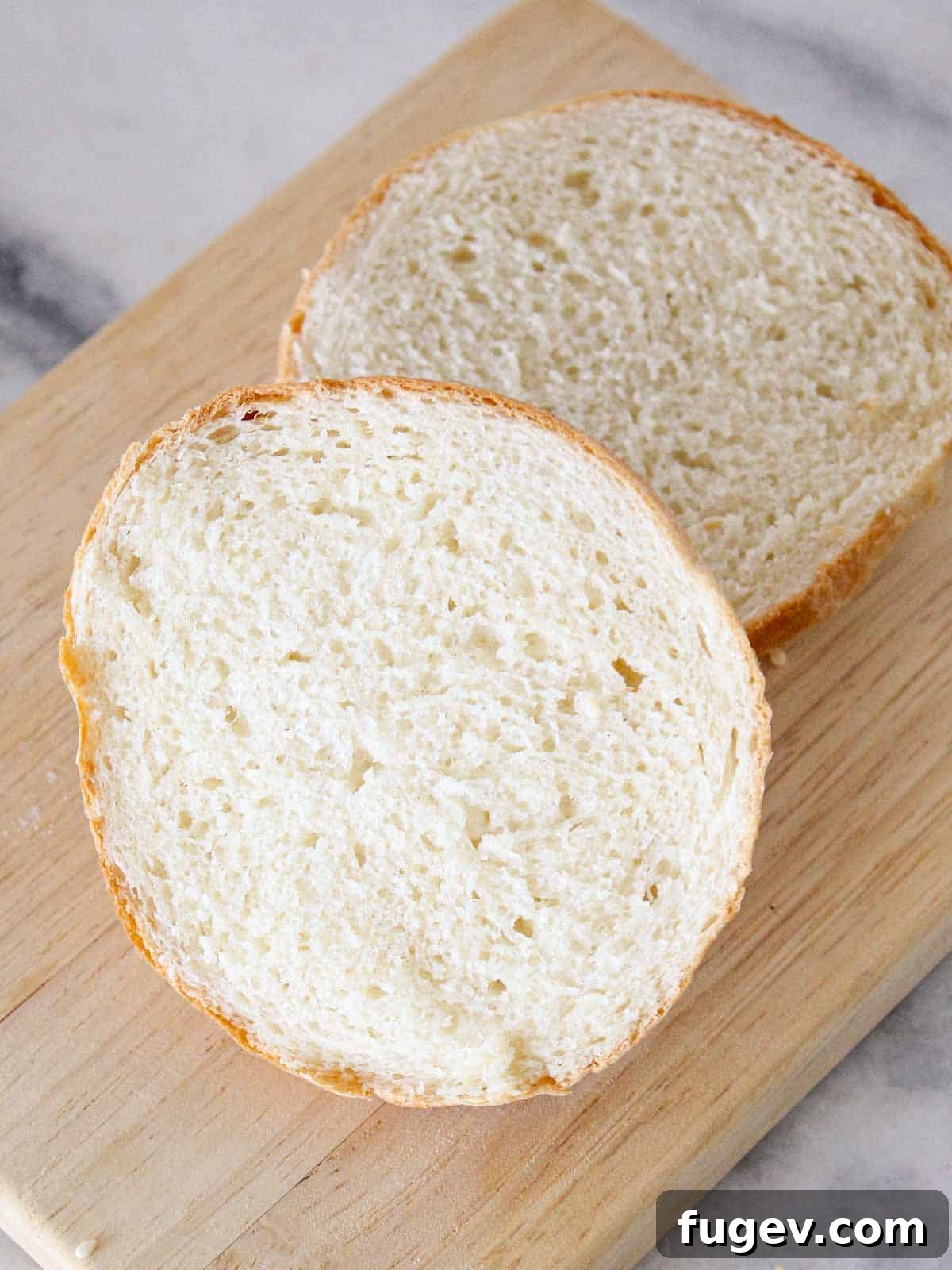 Perfect Fluffy Brioche Buns 3 A freshly baked brioche bun sliced open on a rustic wooden board, showcasing its airy, golden crumb and soft interior.