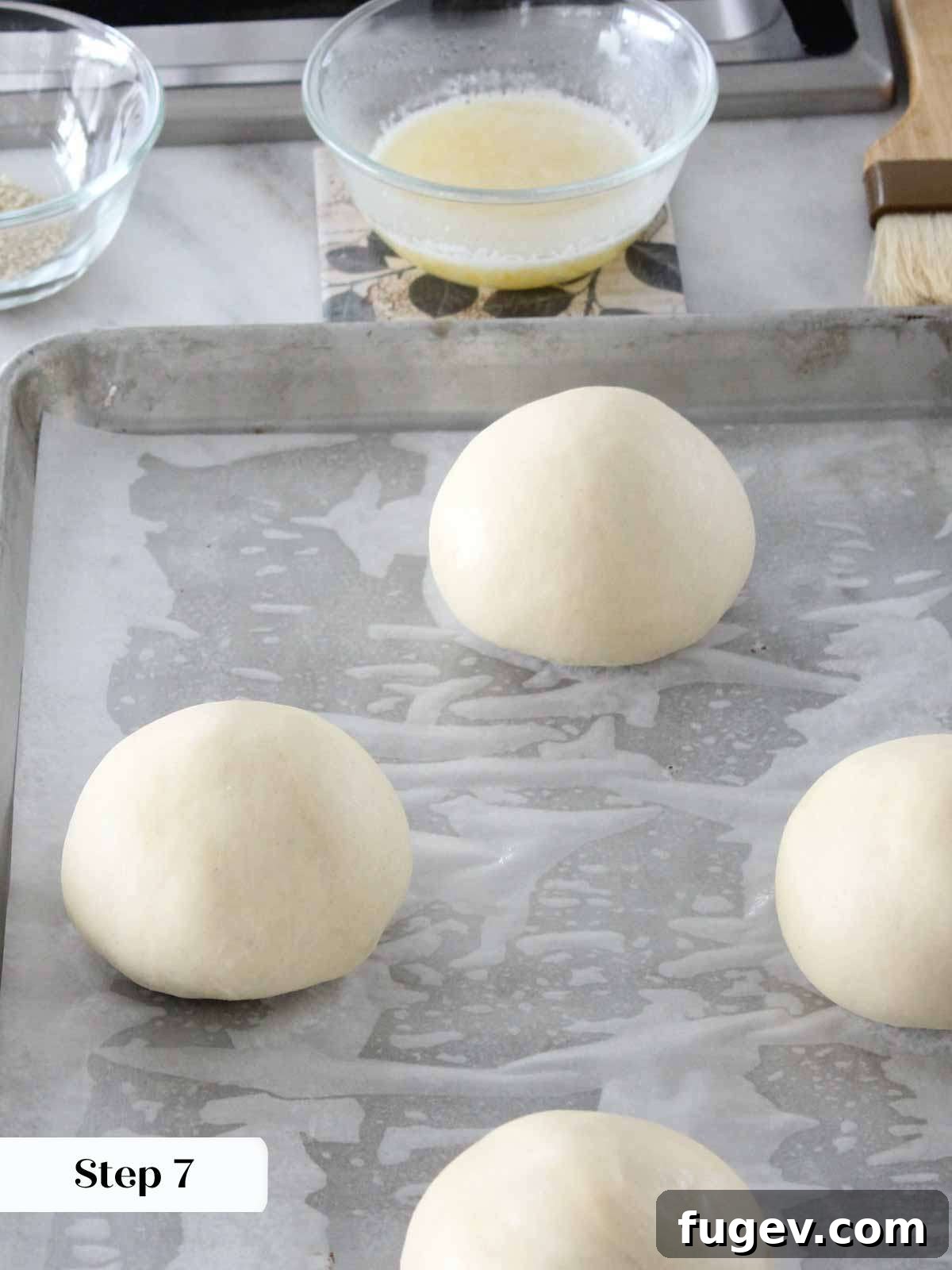 Perfect Fluffy Brioche Buns 5 Perfectly shaped and proofed brioche buns, spaced evenly on a baking sheet, ready for the oven.
