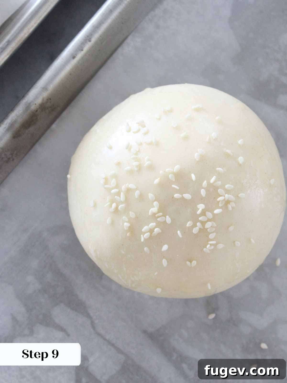Perfect Fluffy Brioche Buns 6 Proofed brioche bun, ready for baking, with white sesame seeds generously sprinkled on top of an egg wash.