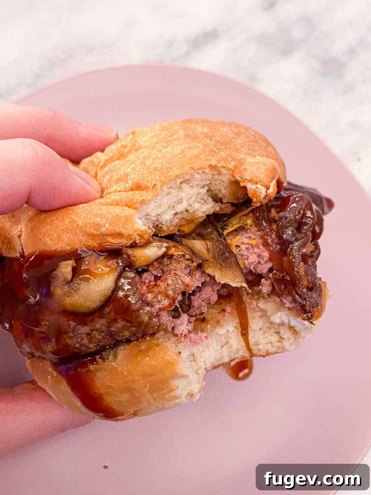 Perfect Fluffy Brioche Buns 7 A hand holding a delicious burger, featuring a perfectly toasted homemade brioche bun, showcasing its soft texture.