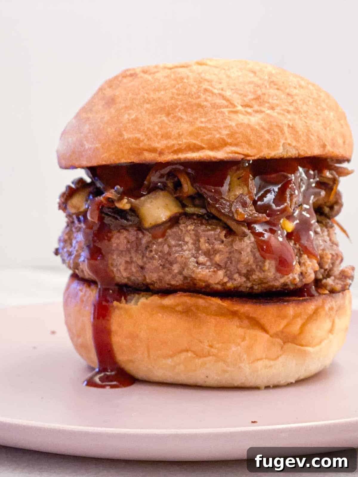 Perfect Fluffy Brioche Buns 8 A towering gourmet burger on a fluffy brioche bun, served on a stylish pink plate, ready to be enjoyed.