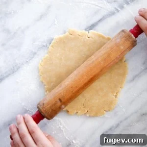 Old Fashioned Almond Pie Crust on marble surface with antique rolling pin
