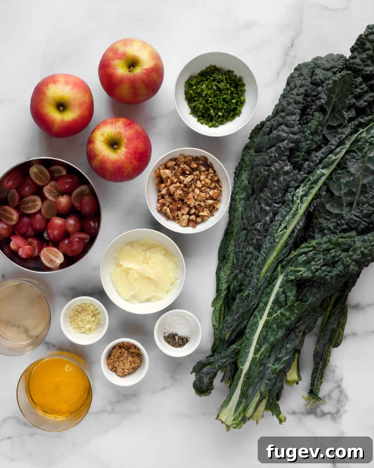 Crisp Apple Kale Salad 3 A flat lay image showing all ingredients for Kale Apple Salad: kale, apples, walnuts, grapes, chives, manchego cheese, garlic, mustard, and olive oil.