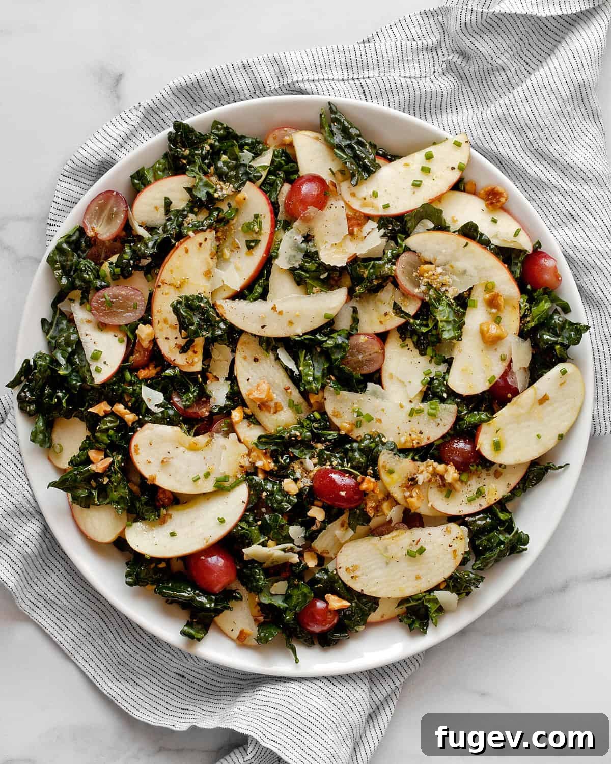 Crisp Apple Kale Salad 6 A single serving of Kale Apple Salad with apples, grapes, and walnuts beautifully arranged on a white plate.