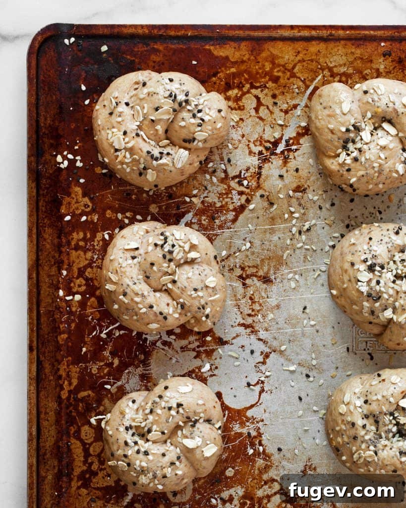 Everything Oat Twists 5 Shaped dough knots arranged on a sheet pan, ready for their second rise
