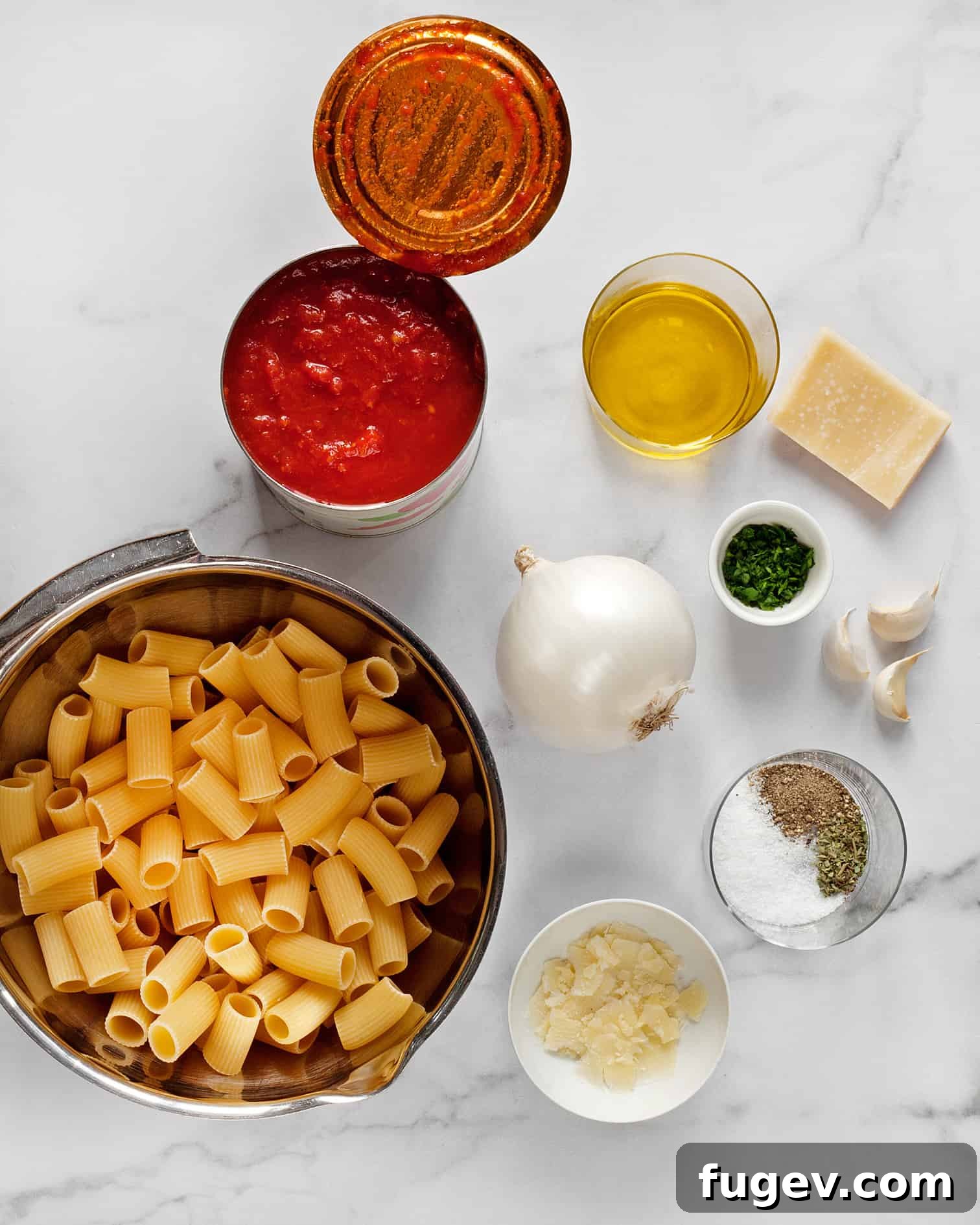 Hearty Rigatoni in Rustic Tomato Sauce 3 A flat lay photograph showcasing all the fresh ingredients needed for rigatoni with tomato sauce, including pasta, canned tomatoes, onion, garlic, and various spices.