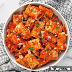 Rigatoni with tomato sauce in a bowl, garnished with fresh herbs.