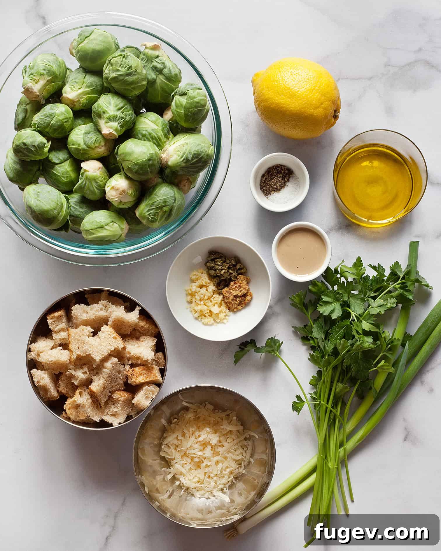 Shaved Brussels Sprout Caesar Salad 3 Assortment of fresh ingredients for brussels sprout Caesar salad including whole brussels sprouts, fresh parsley, lemon, tahini, scallions, olive oil, Parmesan cheese, and sourdough bread.