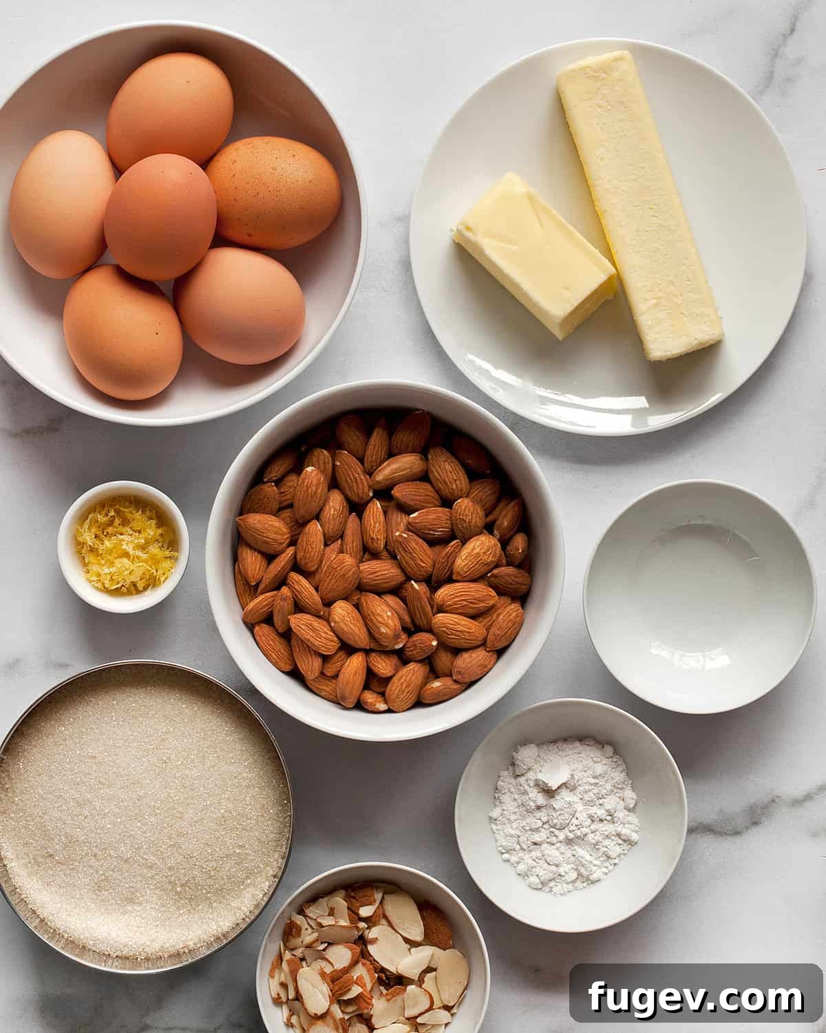 Golden Almond Flour Delight 3 A selection of fresh ingredients laid out: whole almonds, eggs, sticks of butter, a lemon, granulated sugar, and a bottle of almond extract, ready for baking.