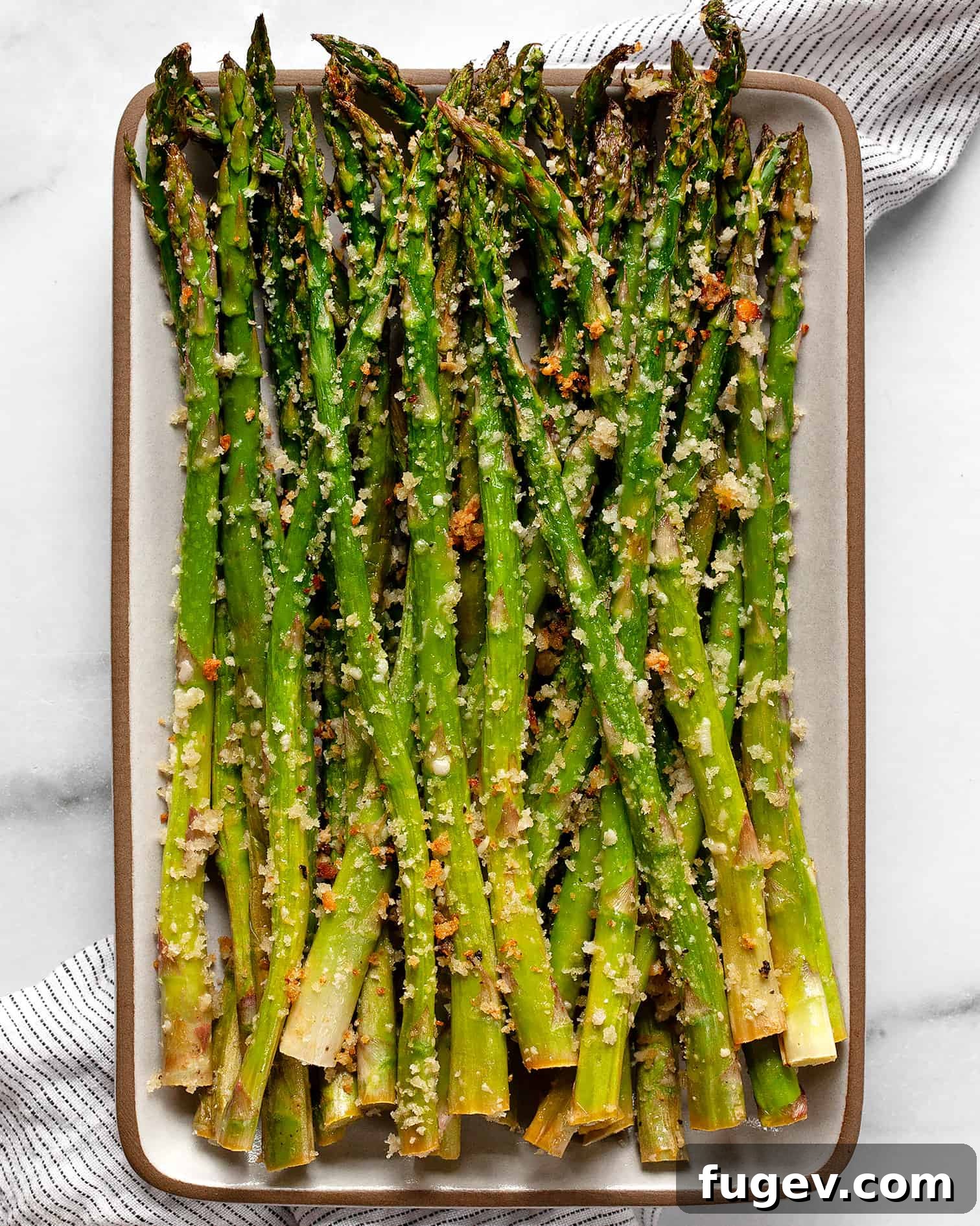 Savory Garlic Parmesan Asparagus 2 Parmesan roasted asparagus on a plate, garnished with fresh lemon wedges.