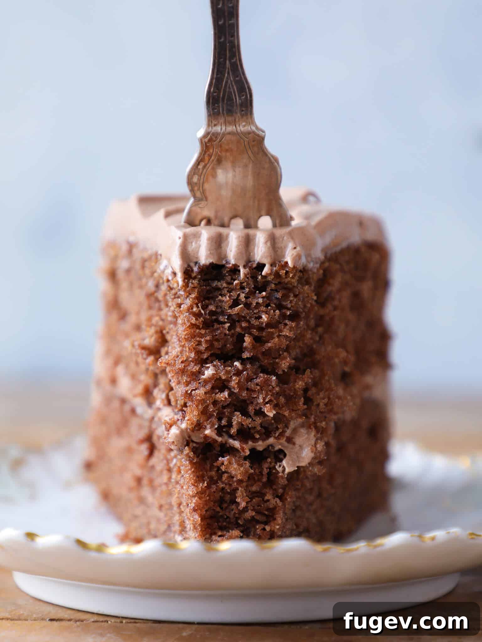 Velvet Fudge Delight 2 A delectable slice of old-fashioned chocolate fudge cake, showcasing its rich, moist interior and creamy icing, with a piece on a fork ready to be enjoyed.