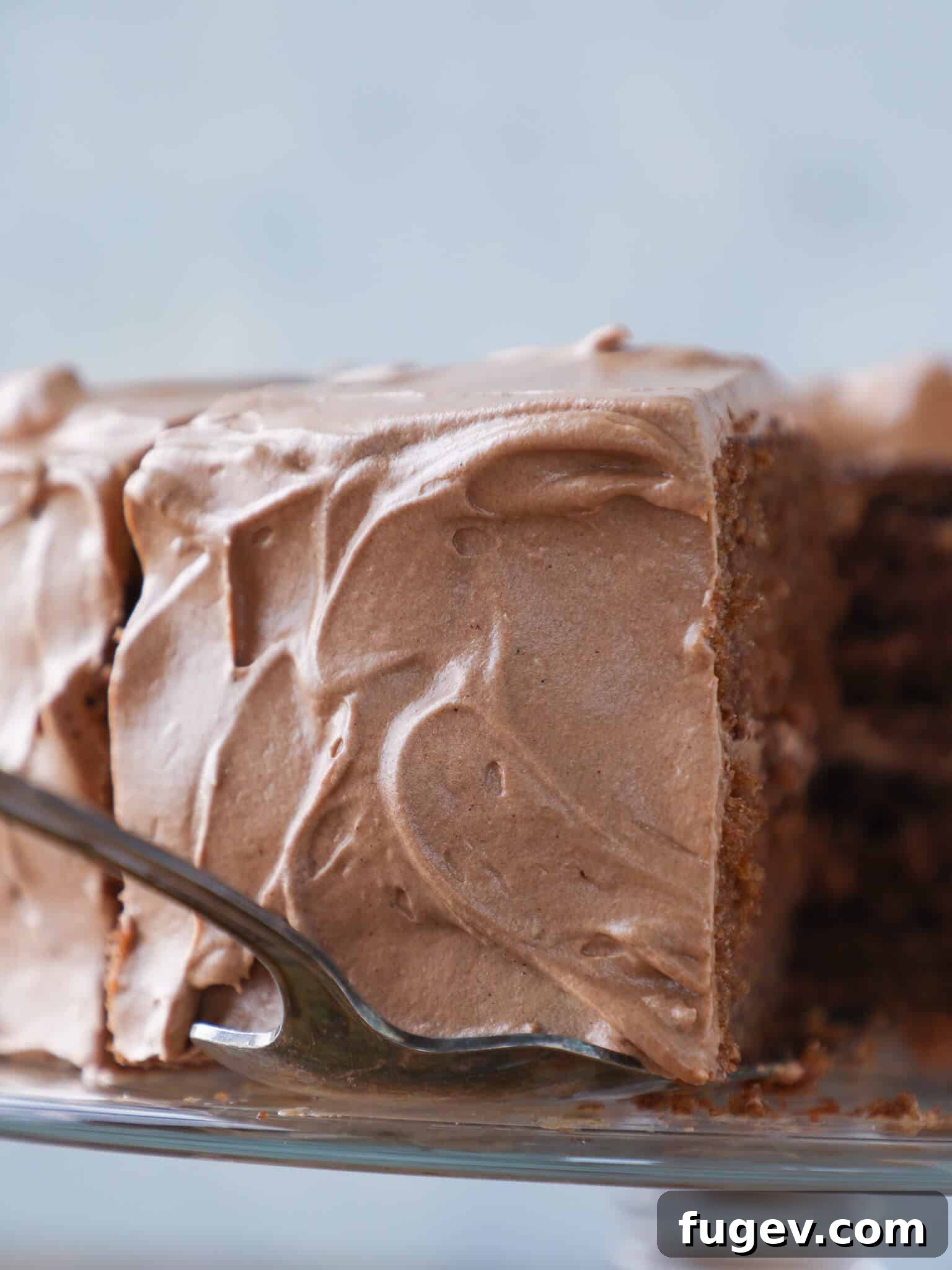 Velvet Fudge Delight 5 A slice of old-fashioned chocolate fudge cake being served, showing beautiful swirls of creamy icing and a rich, moist cake texture.