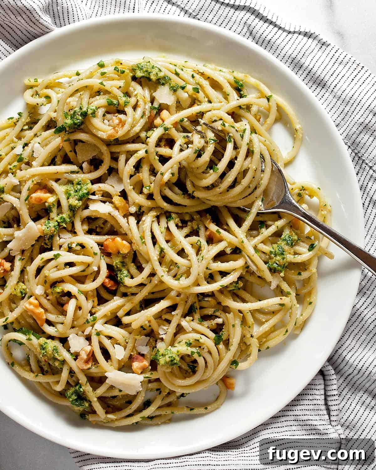 Emerald Pesto Pasta 2 Spaghetti tossed with vibrant green parsley pesto, garnished with fresh herbs on a white plate.