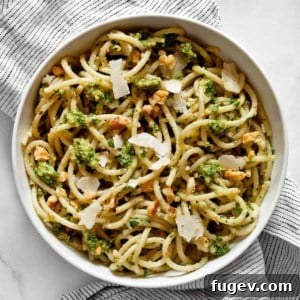 Spaghetti in a bowl tossed with vibrant parsley pesto.