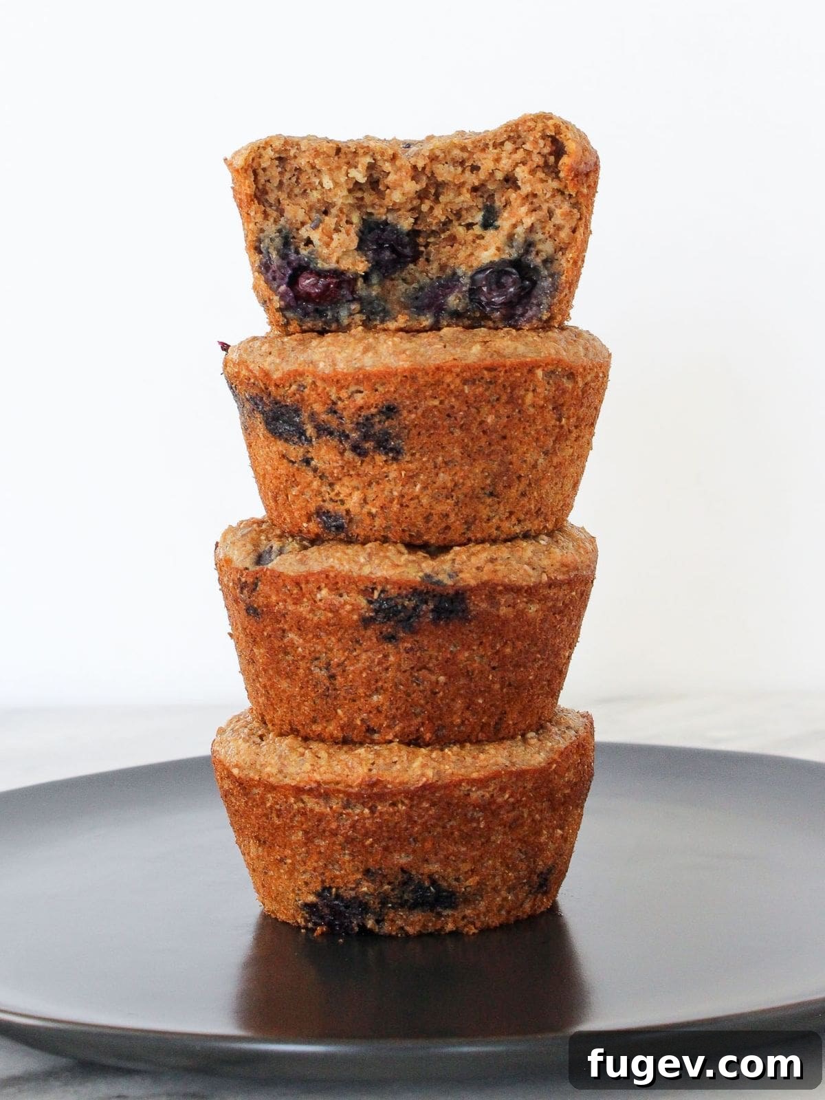 Power-Packed Banana Muffins 2 Freshly baked banana protein muffins stacked neatly on a grey plate, ready for breakfast or meal prep.