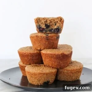 A banana protein muffin with one bite taken, stacked with others to show soft, fibrous inside texture.