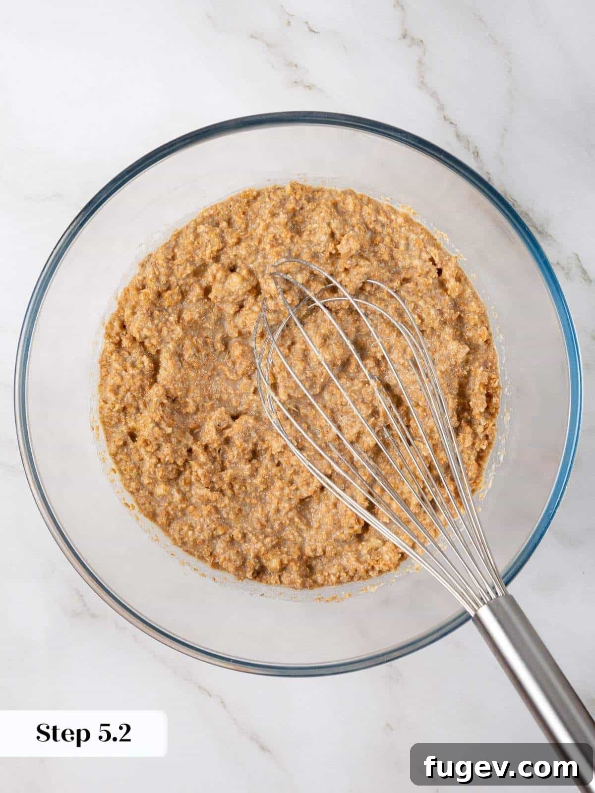 Power-Packed Banana Muffins 8 Wet ingredients including mashed banana, oil, and eggs mixed together until smooth for muffin batter, before dry ingredients are added.