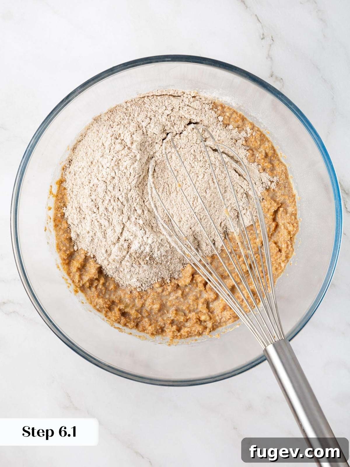 Power-Packed Banana Muffins 9 Flour mixture being added to a bowl of wet ingredients while making banana protein muffin batter.