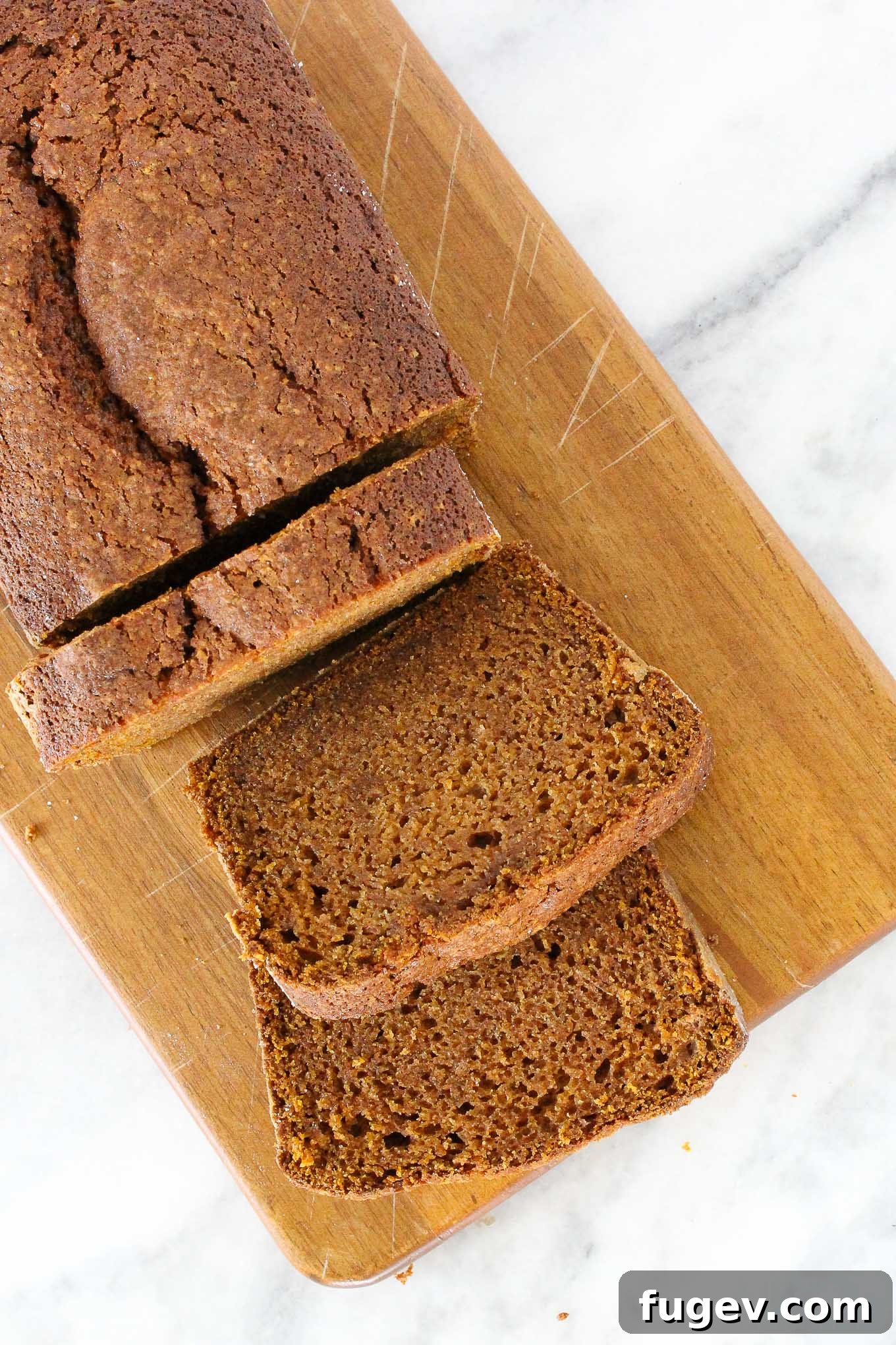 Spiced Pumpkin Delight 2 Sliced pumpkin bread elegantly arranged on a wooden board, showcasing its moist texture and golden crust.