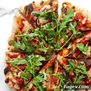 Arugula Pizza with Sun Dried Tomatoes cut into slices, ready to be served.
