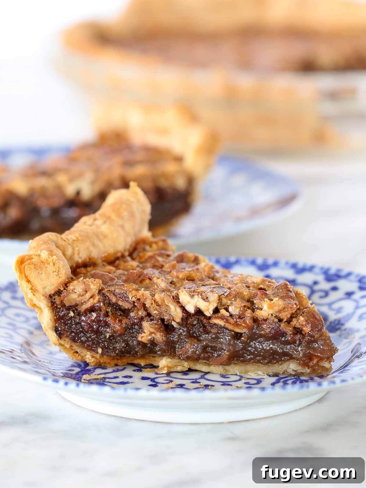 Whiskey-Kissed Pecan Dream 2 Slices of perfectly baked Bourbon Pecan Pie on elegant blue plates, ready to be served.