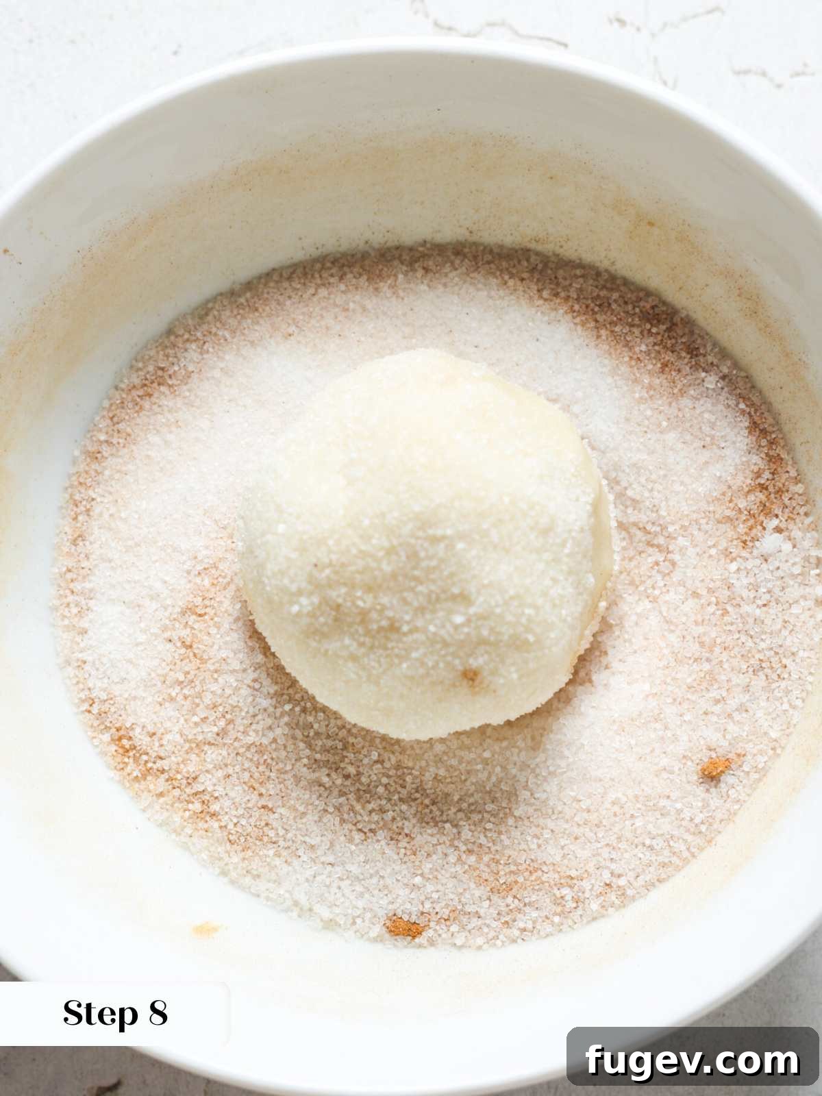 Your New Favorite Snickerdoodle Recipe 9 A snickerdoodle cookie dough ball rolled in cinnamon sugar, ready for baking.