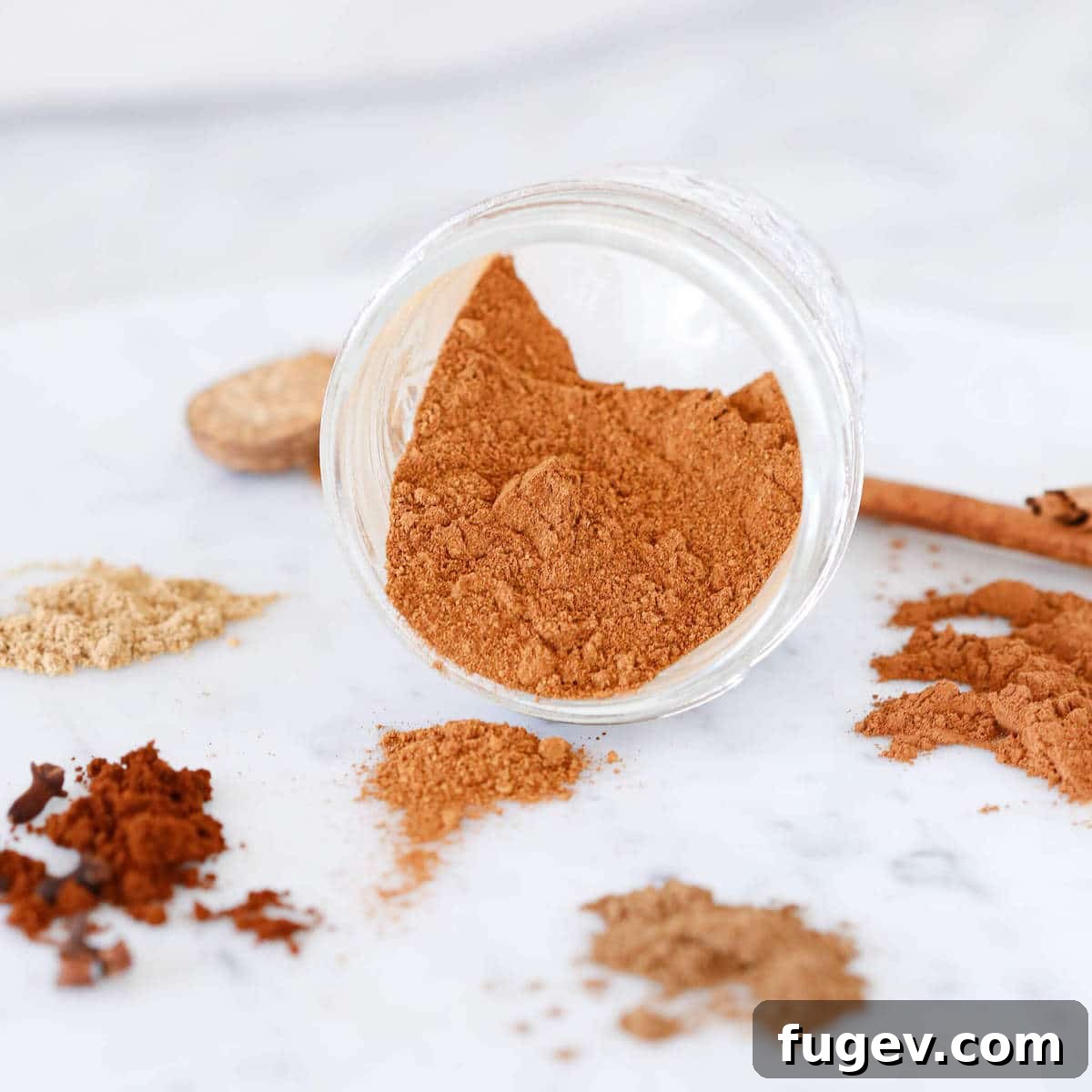 Homemade Pumpkin Spice Delight 6 A mix of whole spices and ground pumpkin spice on a marble surface.