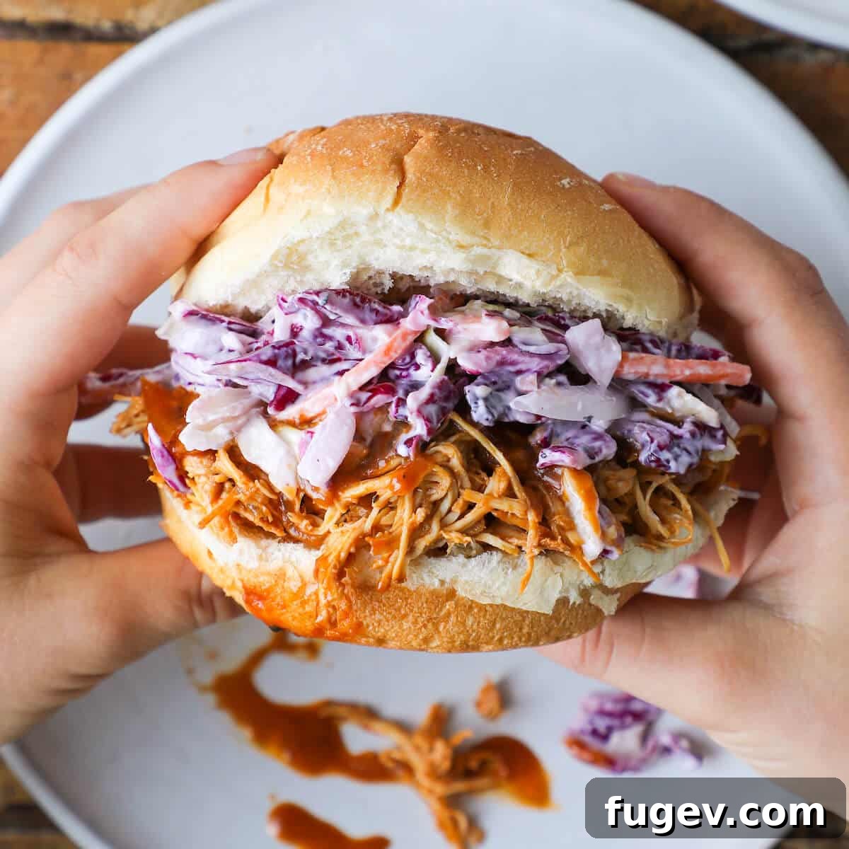 Fall-Apart Slow Cooker BBQ Pulled Chicken Sandwiches 4 Hand holding a slow cooker barbecue pulled chicken sandwich