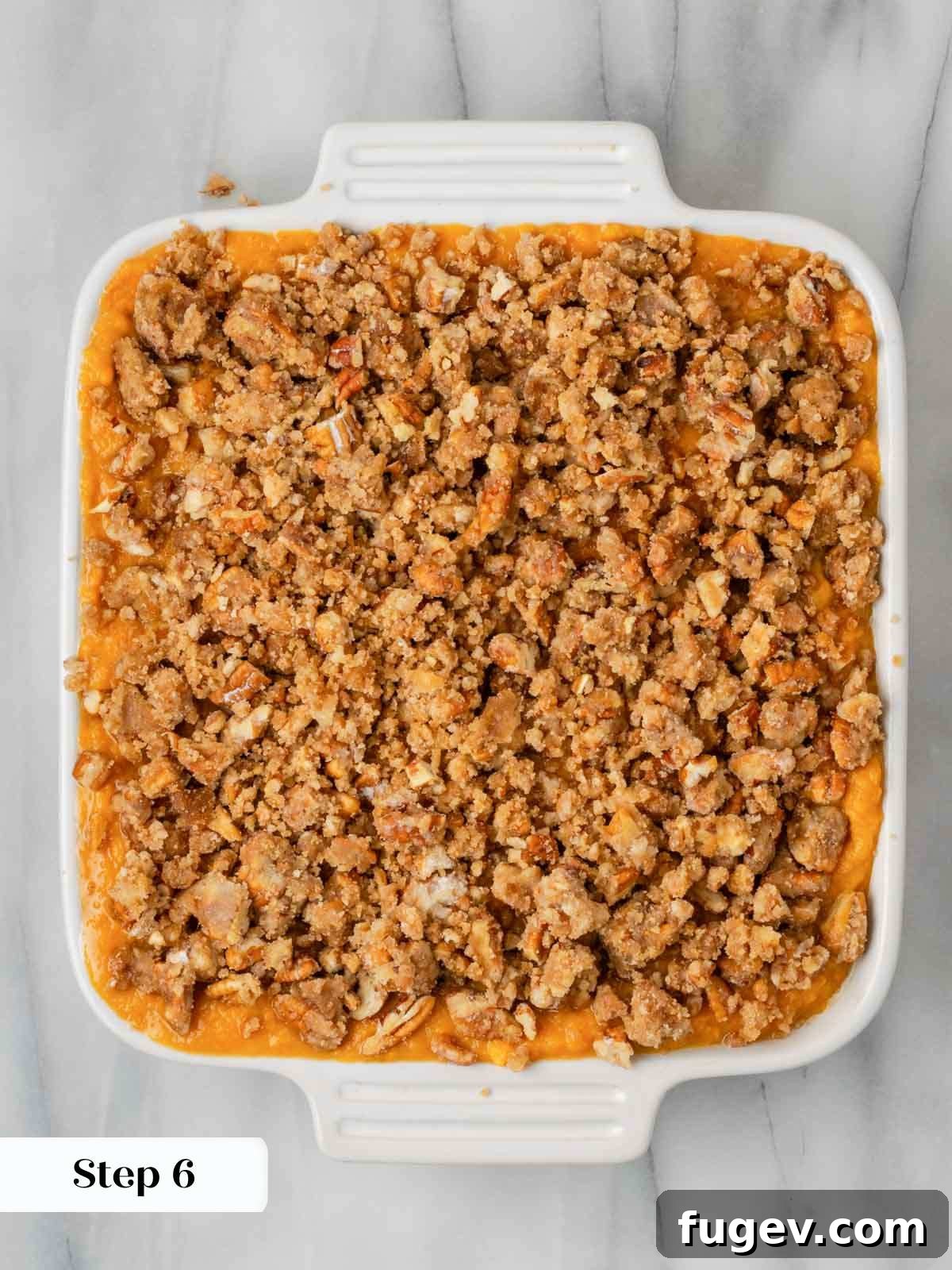 Golden Pecan Sweet Potato Bake 10 Unbaked sweet potato casserole with the pecan streusel topping already sprinkled on top, in a white baking dish.