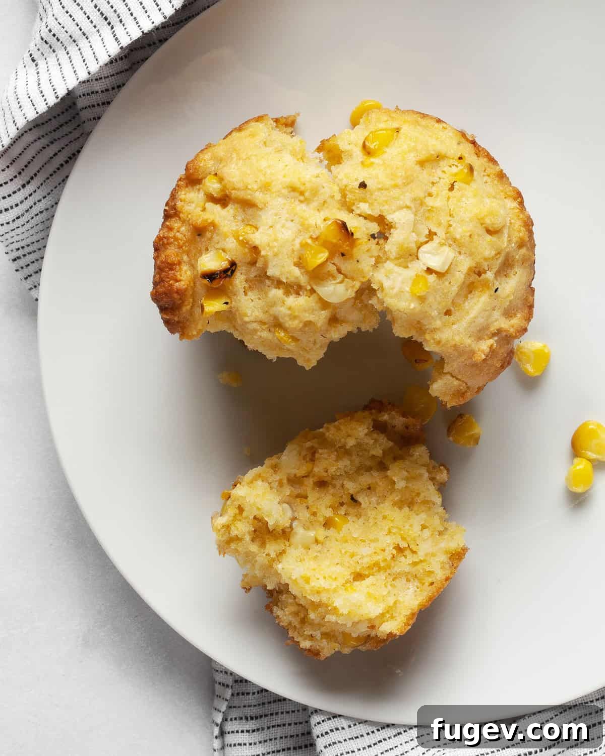 Smoky Sweet Cornbread Muffins 9 A beautifully split cornbread muffin, showcasing its moist crumb and visible corn kernels, resting on a plate.