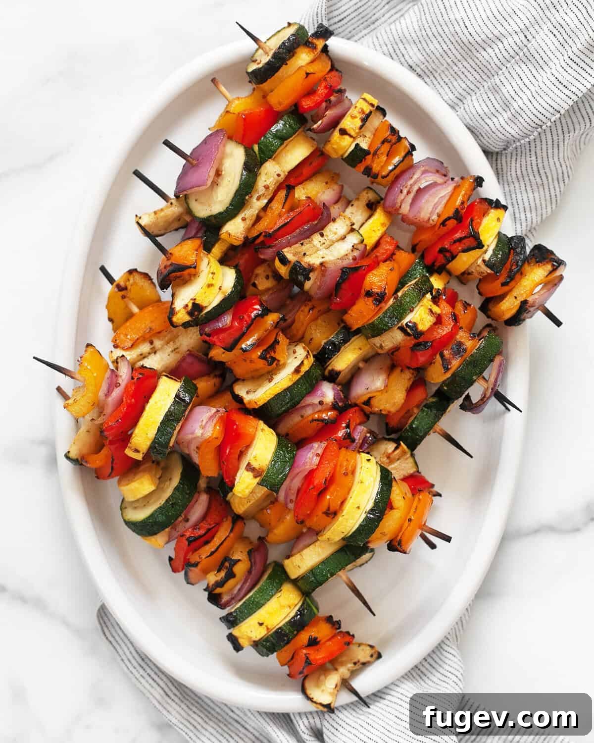 Grilled Rainbow Skewers with Balsamic Drizzle 3 Balsamic grilled vegetable skewers arranged beautifully on an oval serving platter.